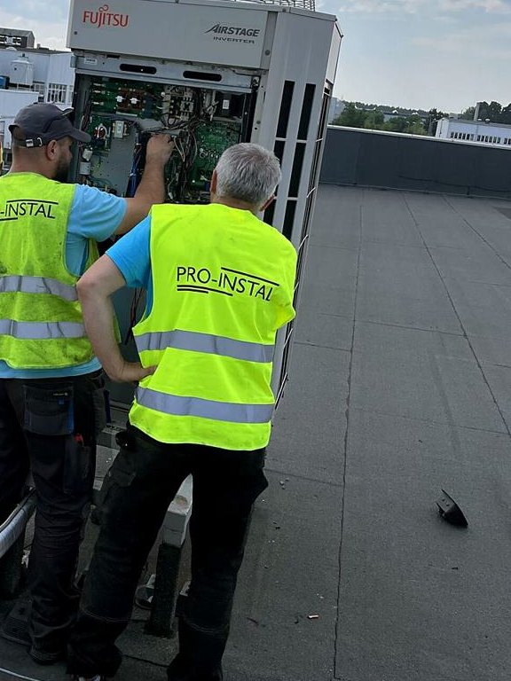 Dwóch serwisantów PRO-INSTAL przy agregacie na dachu