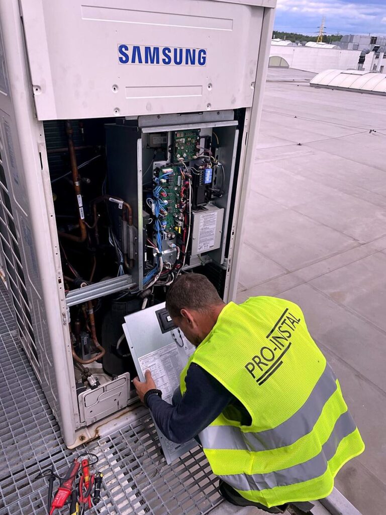 Serwisant PRO-INSTAL przy otwartej jednostce zewnętrznej VRF Samsung